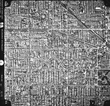 Rooftops, roads, trees and open spaces seen from the air directly above.