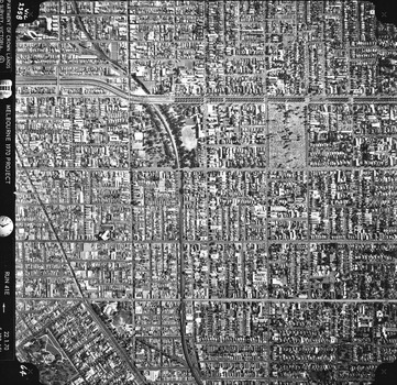 Rooftops, roads, trees and open spaces seen from the air directly above