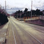 A set of tram tracks extending in a straight line. A second set of track joins them on the right. In the distance is the skyline of Melbourne city. A sign on the left in the foreground says 'pedestrians prohibited'. 