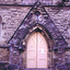 Double solid wood doors, painted yellow, shaped at the top to fit a pointed arch doorway. On the lower half of each door are two recessed rectangular panels, one above the other. On the upper half is a large panel in the shape of a pointed arch and a small panel triangular panel.
