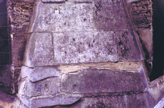 Damaged blocks in a bluestone wall that have been repaired with white mortar 