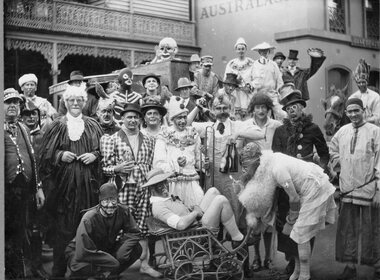 Photograph, B/W photo of a group of People all in fancy dress, in front of Commercial Hotel