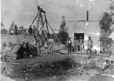 Photograph, Mining Scene with Workmen standing in front of tin shed with simple poppet head in background