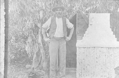 Photograph, Mr Alexander Peters, next to a bag tent with wattle and daub and brick chimney at Deep Lead