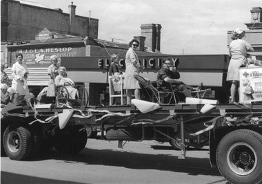 Photograph, Red Cross float in Main Street in front of Mr R.J. & Mr L.A. Heslop Shop and Electricity Showroom