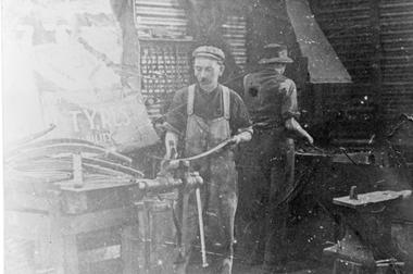 Photograph, Young and Ledgar's Engineering Works with 2 men at a workbench & forge