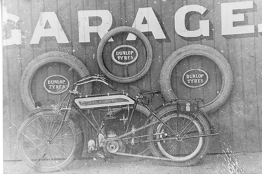 Photograph, Motorbike "The Wimmera" in front of wooden wall with Garage sign on wall. --  Deards and Young and Ledgars Garage