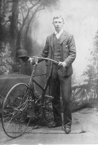 Photograph, Unknown gentleman in a suit standing and holding a Bicycle -- Studio Portrait