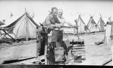 Photograph, Deep Lead -- Bunyip Bank Rail Crossing with 2 men near a fire in front of row of tents where workers were housed