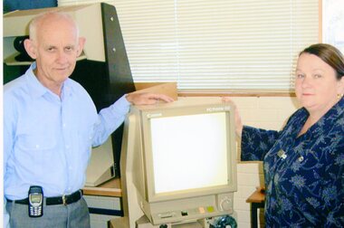 Photograph, Two people in library next to Microfische