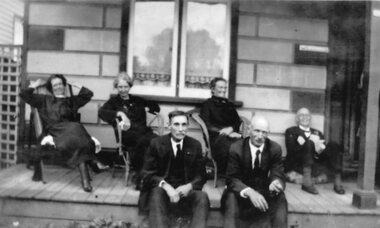 Photograph, Gragg family on front porch of house.  William Cragg seated on verandah at left. Annie woman on right