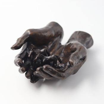 Two life-sized outstretched hands cradle two minature horses 
