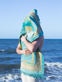 This photograph was the hero image from artist Ayman Kaake's commissioned exhibition at Eltham Library Community Gallery 'In their names' which was Nillumbik Shire's first collaboration with Midsumma Festival.  The work is a self-portrait of the artist at Half Moon Bay in which he is covered by and holds a Prayer Rug.  The back drop is the sea, a significant border between countries in the artists work.