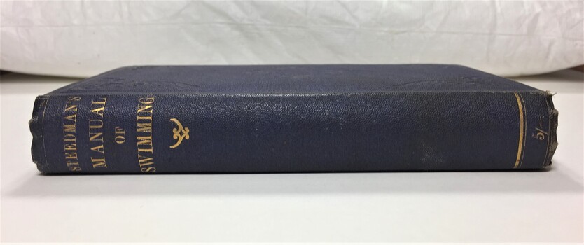 Side view of book showing gilt lettering  "STEEDMAN'S MANUAL OF SWIMMING" at the top of the spine and a price of 5 shillings, also gilt, at the bottom of the spine.