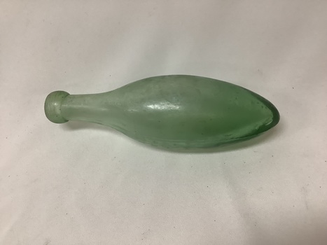 Bullet shaped small green glass bottle, with a short thick mouth. Some bubbles are in the glass, indicating it was probably hand blown. 