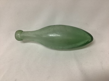 Bullet shaped small green glass bottle, with a short thick mouth. Some bubbles are in the glass, indicating it was probably hand blown. 
