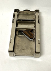 Metal, automatic razor blade sharpener with a sharpening stone, in a red leather case containing printed instructions.