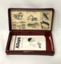 Metal, automatic razor blade sharpener with a sharpening stone, in a red leather case containing printed instructions.