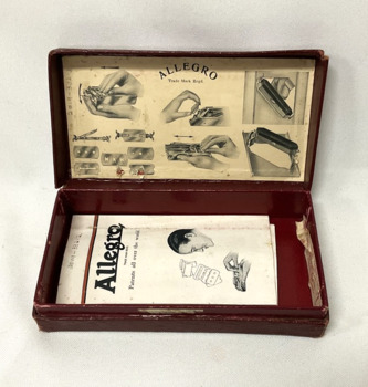 Metal, automatic razor blade sharpener with a sharpening stone, in a red leather case containing printed instructions.