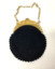 Small circular black cotton crocheted evening handbag, with a cream plastic clasp and a plastic chain link handle. The clasp has a design of four elephants and a depiction of Buddha in the centre. Peacock blue coloured silk lining, with ruched edging.