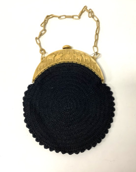 Small circular black cotton crocheted evening handbag, with a cream plastic clasp and a plastic chain link handle. The clasp has a design of four elephants and a depiction of Buddha in the centre. Peacock blue coloured silk lining, with ruched edging.