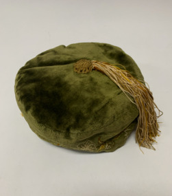 Man’s green velvet smoking cap with a cream, tan and yellow twisted silk tassell on the top, attached by a tan silk crocheted knob. Cream, tan and yellow flowers embroidered around the bottom of the cap. Quilted wool lining. Owned by William Hall, early farmer in Newport.