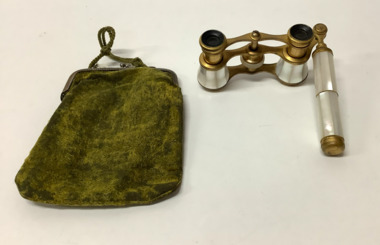 Opera binocular glasses - gold plated metal with mother of pearl covering on an extendable handle also covered in mother of pearl. Extendable handle has knurled tightening bands. Binoculars can be adjusted with knurled wheel.
Carrying purse of pale green velvet attached to a metal purse clasp with green knitted cord attached.
