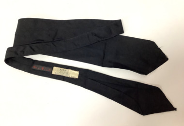 Long black silk tie with sellers label on the back - "M.J. WARD/NELSON PLACE/WILLIAMSTOWN PIER"
