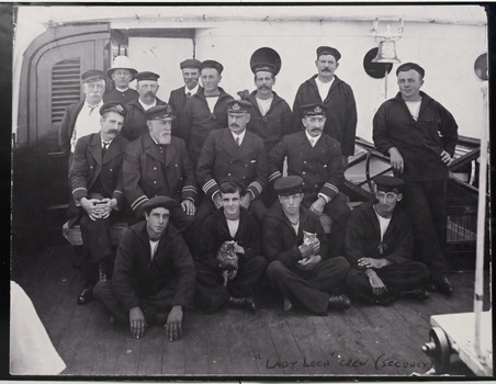 Large black and white group photograph of 16 male crew members of the 'Lady Loch', a Lighthouse Tender.
Crew shown in photograph:
BACK ROW: L to R: J.McEWan, cook; -----------------; Mr. Prince, steward;--------------------;------------------------; Mr. Nelson, fireman.
CENTRE ROW: Mr. Bradley, 2nd officer; Captain Bolger; Mr.Trace, 1st officer (later captain);-------------------.
FRONT ROW: ---------------;Clarence "chicken" Young, seaman (later father of Betty) (holding cat); Doug Geary (holding cat);------------------.