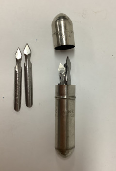 Small bullet-shaped steel container with a lid, holding 18 arrow-shaped, disposable steel styles used for vaccination against smallpox