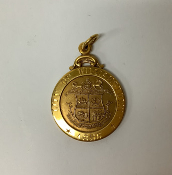 Small 9 carat gold round gold medallion with ring for attaching to a chain or fob. Coat of arms of Williamstown on the face.  Obverse engraved. Commemorating Councillor R A E Ducrow, Mayor of Williamstown from 1948 to 1960. In original cream coloured plastic, square lidded box with burgundy velvet lining.