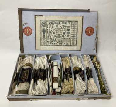 Lidded cardboard box containing a variety of silk and linen sewing thread. The tread is sorted in to hanks, ans grouped into seven small cardboard boxes. The inside of the lid shows drawings of a range of products made by the company.