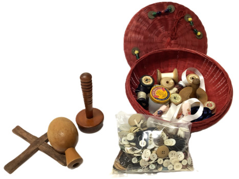 Circular red dyed wicker basket with a lid, containing various sewing and darning implements and other assorted sewing accessories: eight spools of thread, three wooden darning spools and a wooden winding cross, quantity of buttons in a plastic bag, three pieces of ribbon, a metal thimble and a small white glass AGM Marmite jar with a metal lid containing small black buttons (possibly boot buttons). Lid of basket is decorated with four sets of coloured glass beads and eight chinese coins.