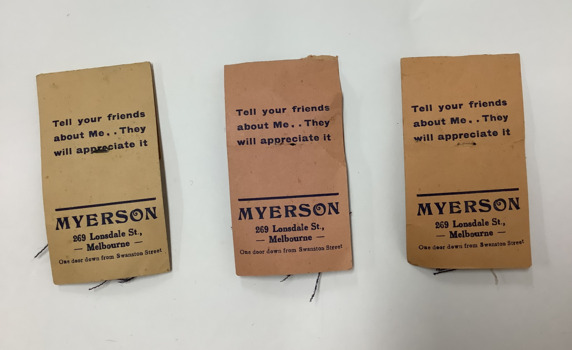 Back view of three Myerson suit or costume fabric samplers: small fabric samples stapled to a cardboard card. 