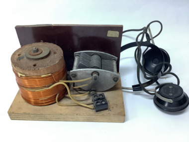 Vintage crystal radio set, home made, on a wooden stand; consisting of a coil (inductor); a tuning capacitor for selection of AM radio stations; headphones manufactured in Japan in the 1950's.