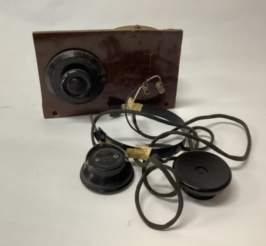 Vintage crystal radio set, home made, on a wooden stand; consisting of a coil (inductor); a tuning capacitor for selection of AM radio stations; headphones manufactured in Japan in the 1950's.
