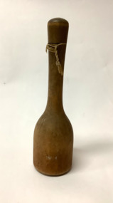 Wooden sugar pounder, bell shaped with a flat base, carved from one piece of wood. Knotted string hanger. 