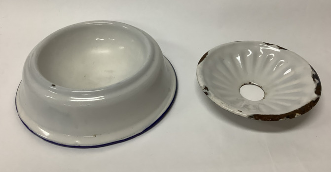 White enamel soap dish with a blue rim around the base of the bowl - an enamel insert with a large hole holds the soap and drains water into the dish. 