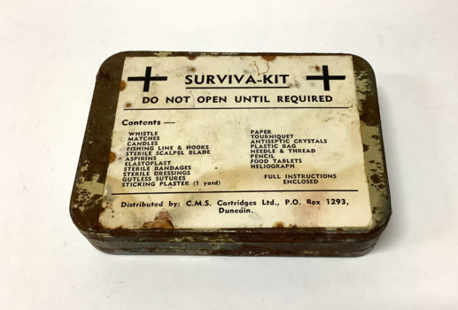 'Surviva-Kit' in an lidded tin box, containing a range of items that would help survival, such as matches, fishing line and hook, and medical items. The tin box has a list of the items printed in black font on a paper label on the lid.