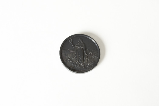 Back side of a small, round, dark-coloured medal. Inscribed on the medal is: The Royal Agricultural Society of Victoria / Busse & Son / 1895