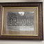 Carved timber frame containing photograph of a platoon of standing and seated WW1 soldiers.