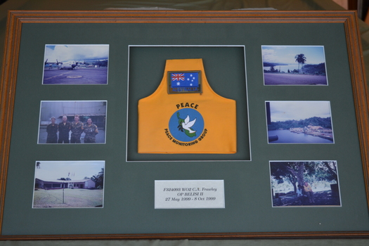 Brown timber frame  containing six photographs and yellow brassard