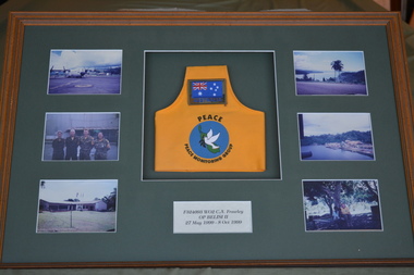 Brown timber frame  containing six photographs and yellow brassard