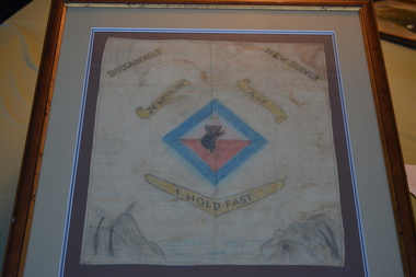 Hand sketch of a koala in a blue diamond above a boomerang on cloth 