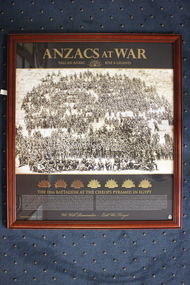 Timber  frame housing a poster/photograph taken of  the 11th Battalion  soldiers standing and sitting on the Cheops pyramid in Egypt. 