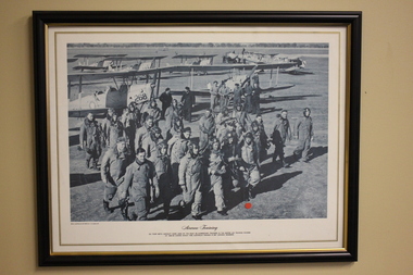 Black frame containing black and white photograph of airmen with aircraft in background