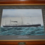 Timber framed print of a ship at sea.  The grey mount has signatures in white paint across the top and sides.