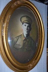 Gold coloured oval frame with sepia photograph of WW1 Soldier wearing cap