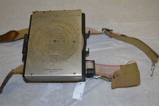 Black metal box with silver metal flap top cover affixed with  rotating circular rule .  Two  adjustable belts are affixed to the base of  black box.   
 
 