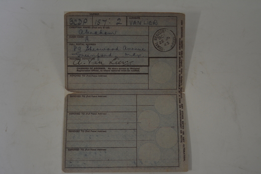 Small folded cardboard of grey colour with pale blue background in centre.  Has black lettering and crest.